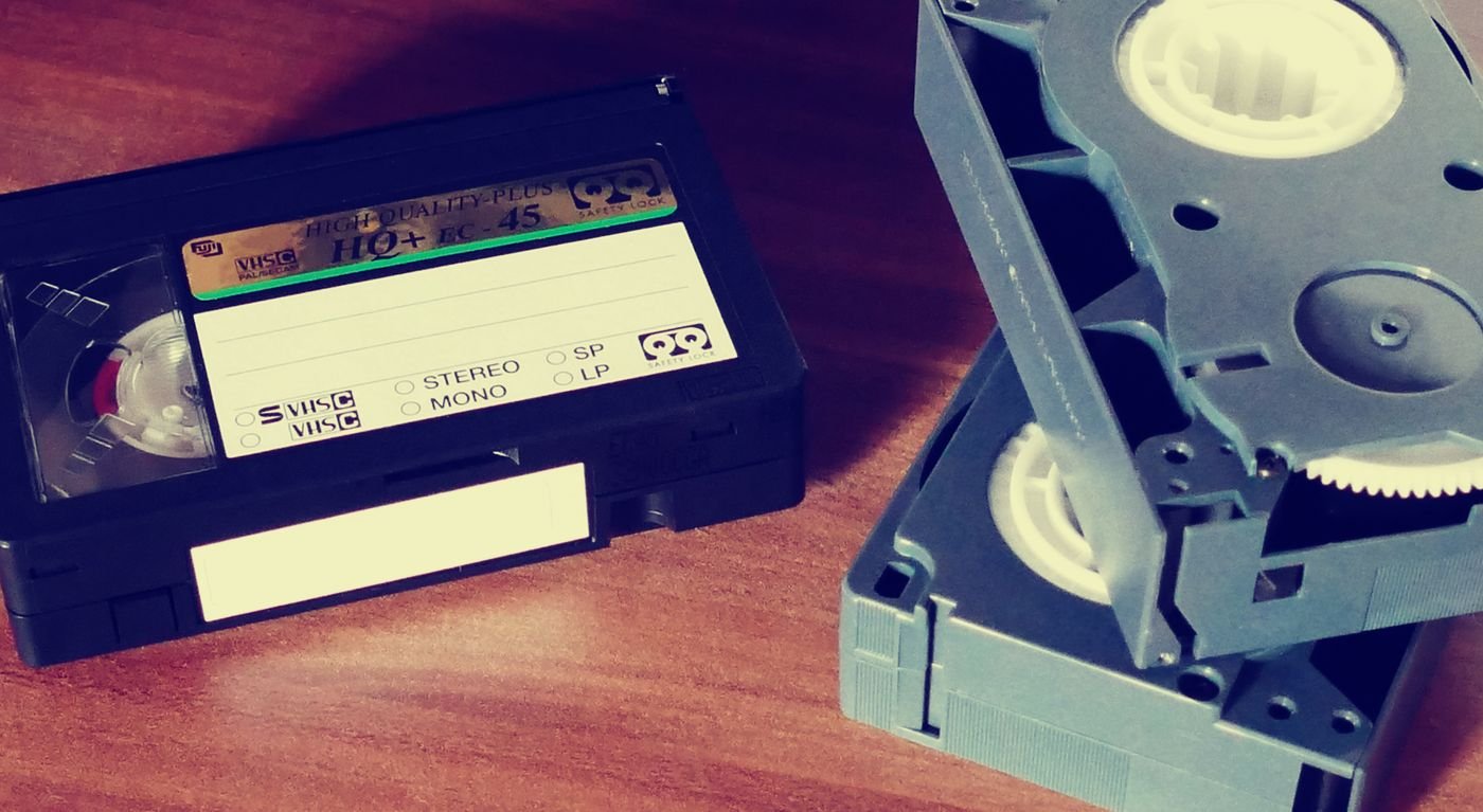 Two home-recorded VHS cassettes with blank white labels lying on a wooden table